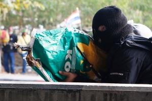 An anti-government protester shoots his rifle, hidden it inside a sack, toward pro-government protesters during clashes in Bangkok February 1, 2014. Dozens of gunshots and at least two explosions raised tension amid anti-government protests in Thailand's capital on Saturday, a day ahead of a general election seen as incapable of restoring stability in the deeply polarised country. REUTERS/Nir Elias (THAILAND - Tags: POLITICS CIVIL UNREST)